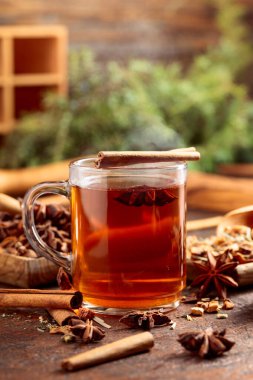 Tarçınlı, anasonlu ve kurutulmuş otlu Noel çayı. Eski kahverengi bir masada, ahşap tabaklarda baharatlı bitki çayı..