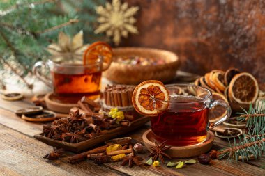 Tarçın, anason ve kuru narenciye dilimli Noel çayı. Eski ahşap bir masada malzemeli bitki çayı..