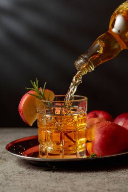 Elma şarabı şişeden bardağa dökülür. Eski bir mutfak masasında elmalı taze içecek. Boşluğu kopyala.