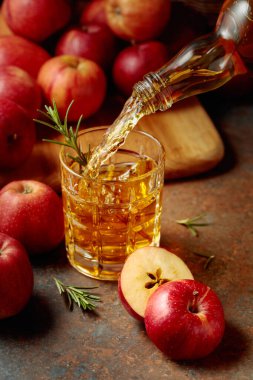 Elma şarabı şişeden bardağa dökülür. Eski bir mutfak masasında elmalı taze içecek..