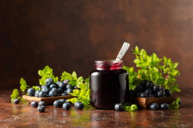 Kahverengi arka planda yabanmersini reçeli ve taze böğürtlen.