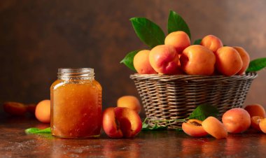 Cam kavanozda kayısı reçeli ve kahverengi bir masada taze meyve. Boşluğu kopyala.
