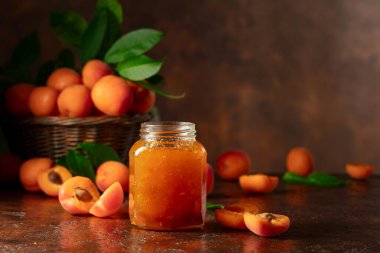 Cam kavanozda kayısı reçeli ve kahverengi bir masada taze meyve. Boşluğu kopyala.