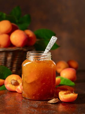 Cam kavanozda kayısı reçeli ve kahverengi bir masada taze meyve. Boşluğu kopyala.