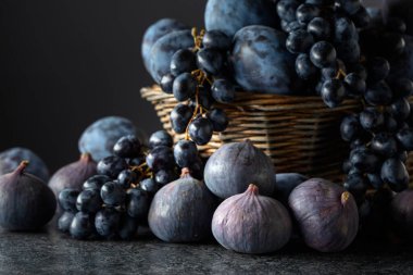 Sulu taze mavi meyveler. Mavi üzümler, mavi erikler ve siyah taş bir masada incir. Boşluğu kopyala.