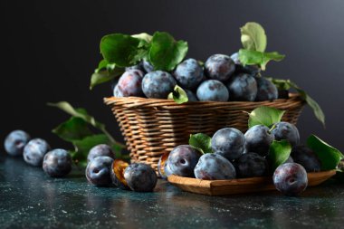 Mutfak masasında yaprakları olan olgun mavi erikler..