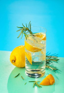 Cin, tonik, limon ve biberiyeyle taze kokteyl. Buzda servis ediliyor, renk ve tazelikle dolup taşıyor. Parlak renkli arkaplan.