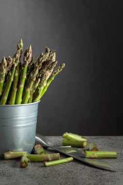 Gri arka planda küçük kovada taze kuşkonmaz. Boşluğu kopyala.