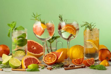 Beyaz mermer bir masada malzemelerle yaz kokteyllerini tazeliyorum. Mojito ve yeşil arka planda çeşitli cin tonik kokteylleri..