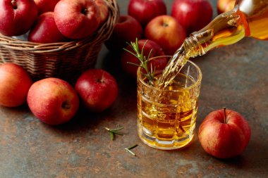 Apple kombucha şişeden bardağa dökülür. Eski bir mutfak masasında elmalı taze içecek..