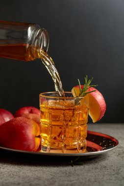 Apple kombucha şişeden bardağa dökülür. Eski bir mutfak masasında elmalı taze içecek. Boşluğu kopyala.