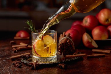 Elma kombu çayı şişeden kristal bardağa dökülür. Eski bir mutfak masasında elmalı taze içecek. Boşluğu kopyala.