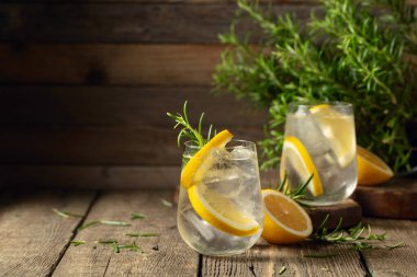 Eski ahşap bir masada buzlu, limonlu ve biberiyeli cin tonik. Boşluğu kopyala.