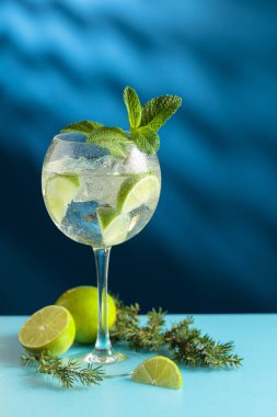 Kokteyller, buzlu cin tonik ve mavi arka planda limon dilimleri. Boşluğu kopyala.