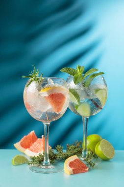 Kokteyller cin tonik, greyfurt ve mavi arka planda limon dilimleri. Boşluğu kopyala.