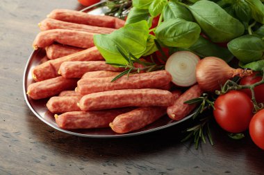 Eski ahşap bir masada fesleğen ve domatesli sosisler..