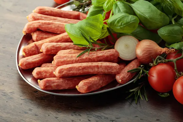 Eski ahşap bir masada fesleğen ve domatesli sosisler..