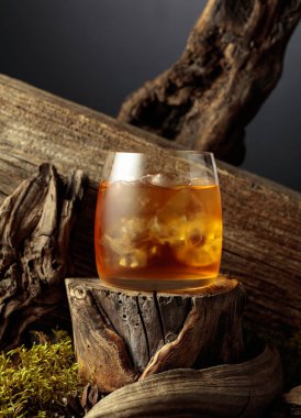 Eski bir kütüğün üzerinde buzlu viski. Sis bardağında soğuk, ferahlatıcı bir içecek..