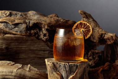 Eski moda bir karışım, buz ve kurutulmuş portakal dilimi ile eski ahşap bir kütükte.. 