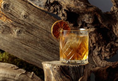 Eski moda bir karışım, buz ve kurutulmuş portakal dilimi ile eski ahşap bir kütükte.. 