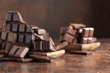 Kahverengi bir arka planda kırık acı ve sütlü çikolatalar..