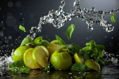 Siyah arka planda limon ve taze nane dalları. Serinletici içecekler ve su sıçraması için gerekli malzemeler. Boşluğu kopyala.