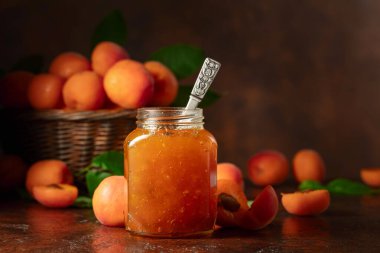 Cam kavanozda kayısı reçeli ve kahverengi bir masada taze meyve. Boşluğu kopyala.