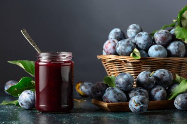 Lacivert arka planda erik reçeli ve taze böğürtlen. Mutfak masasında reçelli olgun erikler..