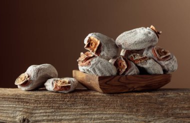 Kahverengi arka planda ahşap bir kapta kurutulmuş hurma. Boşluğu kopyala.