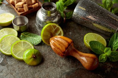 Tahta narenciye sıkacağı, karıştırıcı ve yaz ferahlatıcı içecekler yapmak için malzemeler. Esmer şeker, limon ve taş bir masada taze nane dalları..