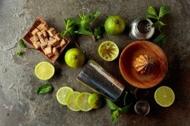 Tahta narenciye sıkacağı, karıştırıcı ve yaz ferahlatıcı içecekler yapmak için malzemeler. Esmer şeker, limon ve taş bir masada taze nane dalları..