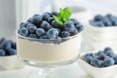 Mascarpone kreması, beyaz ahşap bir masada temiz bir kasede taze yaban mersini. Nane şekeriyle süslenmiş çilekli parfüm..