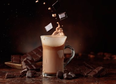 Acı çikolata parçaları cam bardağa dökülür kakao içeceği ile güzel su sıçratır. Boşluğu kopyala.