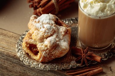 Gümüş tepside Viyana usulü turta ve sütlü kahve. Anason ve tarçınlı taze hamur tatlısı üzerine şeker serpiştirilmiş..