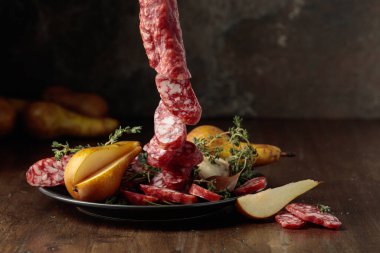 Kurumuş sosisler kekik ve armutlarla eski ahşap bir masada. Basit sağlıklı yiyecekler. Boşluğu kopyala.