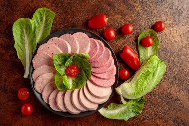 Kahverengi bir arka planda yeşil ve sebzeli çeşitli haşlanmış sosisler..