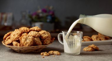 Mutfak masasında yulaflı kurabiye ve süt. Süt şişeden cam bardağa dökülür. Boşluğu kopyala.