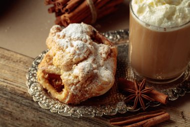 Gümüş tepside Viyana usulü turta ve sütlü kahve. Anason ve tarçınlı taze hamur tatlısı üzerine şeker serpiştirilmiş..