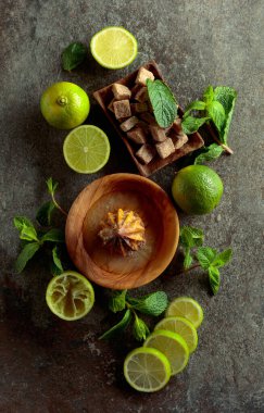 Tahta narenciye sıkacağı ve yaz ferahlatıcı içecekler yapmak için malzemeler. Esmer şeker, limon ve taş bir masada taze nane dalları. Üst görünüm.