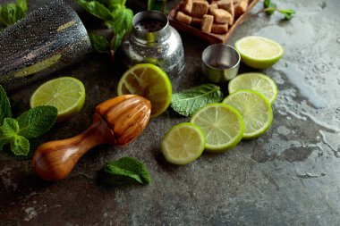 Tahta narenciye sıkacağı, karıştırıcı ve yaz ferahlatıcı içecekler yapmak için malzemeler. Esmer şeker, limon ve taş bir masada taze nane dalları..