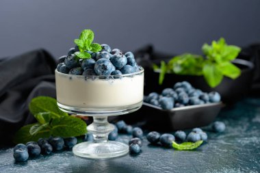 Temiz bir kasede taze yaban mersinli krema. Nane şekeriyle süslenmiş çilekli parfüm..