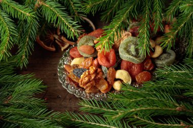 Gümüş tepside çeşitli kurutulmuş meyve ve fındıklar. Vejetaryen tatlısı ve Noel ağacı dalları eski ahşap bir masada..