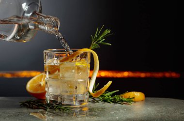 Limon ve biberiyeli cin tonik kokteyli. İçki şişeden buzlu bir bardağa dökülür. Boşluğu kopyala.