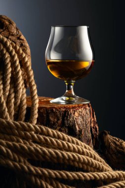 Eski bir kütüğe konyak ve ip. Viski, konyak ya da koyu bir arka planda konyak..