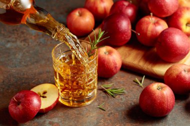 Elma şarabı şişeden bardağa dökülür. Eski bir mutfak masasında elmalı taze içecek..