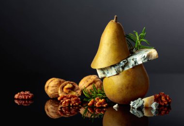 Armut, ceviz ve biberiyeli mavi peynir. Siyah yansıtıcı arka planda küflü peynir. Boşluğu kopyala.