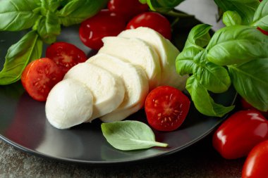 Vişne domatesli Mozzarella peyniri ve siyah tabakta fesleğen..