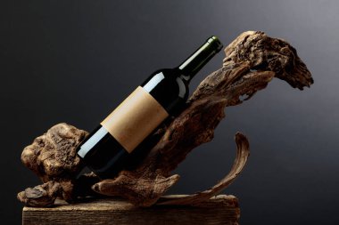 Bir şişe kırmızı şarap ve üzerinde eski bir etiket var. Ürün markalaşması, kimlik ve ambalaj için siyah arkaplan üzerine minimalist kompozisyon. Boşluğu kopyala.