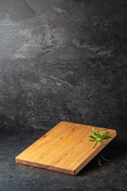 Siyah taşlı arka planda biberiyeli boş kesim tahtası. Boşluğu kopyala.