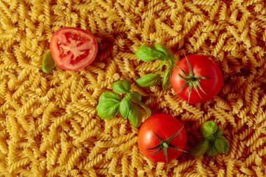 Domatesli ve fesleğenli pişmemiş fusilli makarna. İtalyan mutfağı. Üst görünüm.